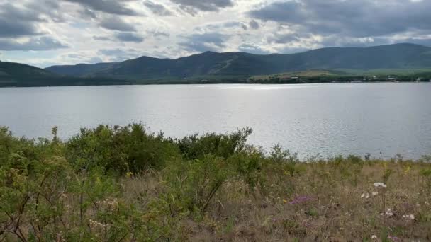 Paisaje de verano. Cielo dramático. Lago de montaña. Hermoso fondo borroso. Un gran campo verde con árboles y montañas en el fondo. Un cuerpo de agua con una montaña en el fondo — Vídeo de stock