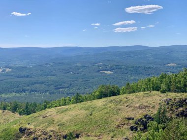Harika bir panoramik manzara. Mavi dağlar ve gökyüzü, yeşil tepeler. Dağın yamacında bir işaret.