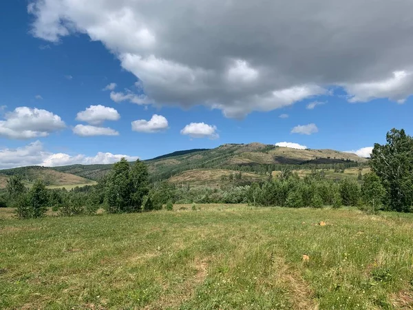 全景全景。美丽的夏季风景。群山蓝天绿地森林天空中的一群云彩.皮克的陆地爬行背景。旅游、旅行、远足概念. — 图库照片