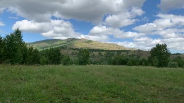 Panoramik manzara. Güzel yaz manzarası. Dağlar, mavi gökyüzü ve yeşil tarlalar, gökyüzündeki bir grup bulut