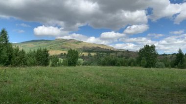 Panoramik manzara. Güzel yaz manzarası. Dağlar, mavi gökyüzü ve yeşil tarlalar, gökyüzündeki bir grup bulut