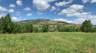 Panoramik manzara. Güzel yaz manzarası. Dağlar, mavi gökyüzü ve yeşil tarlalar, gökyüzündeki bir grup bulut