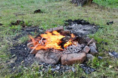 Dağların ve huş ağaçlarının arka planına karşı çayırda şenlik ateşi.