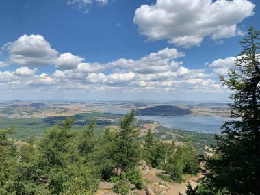 Yaz manzarası Dağların ve mavi gökyüzünün arka planına karşı temiz dağ gölü. Suyun yanında kumlu bir sahil.