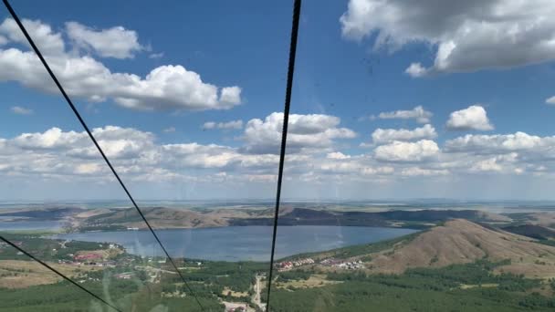 4K-video Skytte från hytten i en flyttbar hiss till berget. Panoramautsikt över berg, sjöar och skogar Blå himmel — Stockvideo