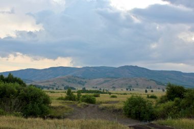 Gün batımında yaz manzarası. Tarlalardan ve ormanlardan oluşan dağların güzel panoramik manzarası