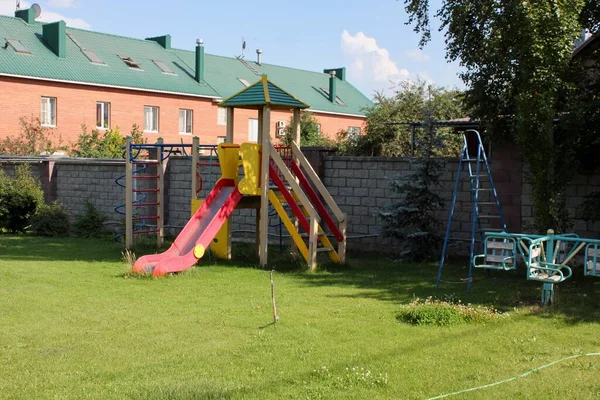 Dětské hřiště ve dvoře bytového domu na ulici se skluzavkami, schody, s houpačkami — Stock fotografie