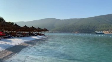 4K Güzel panoramik cennet manzaralı plaj beyaz kumlu, yatlı, göl kıyısında Ege Denizi 'nin zümrüt suyuyla kaplı evler, lüks turizm kavramı.