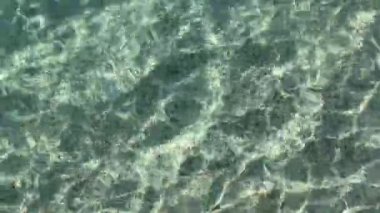 4K kristal berrak zümrüt deniz suları, kumlu taban, Ege Denizi 'nin temiz gölgeleri ve renkleri. Güzel, saf doğa çekimi.