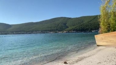 4K Güzel panoramik cennet manzaralı plaj beyaz kumlu, yatlı, göl kıyısında Ege Denizi 'nin zümrüt suyuyla kaplı evler, lüks turizm kavramı.