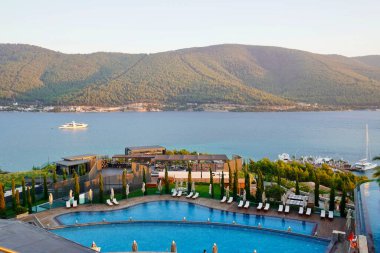 Bodrum, Türkiye - Ağustos 2020: Hotel Beach Lujo. Cennet 'te tatil. Güzel tropikal plaj afişi. Beyaz kum turizmi geniş panorama arka plan konsepti. İnanılmaz sahil manzaraları, yatlar.