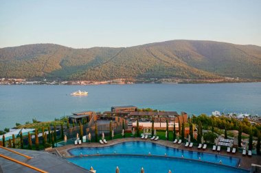 Bodrum, Türkiye - Ağustos 2020: Hotel Beach Lujo. Cennet 'te tatil. Güzel tropikal plaj afişi. Beyaz kum turizmi geniş panorama arka plan konsepti. İnanılmaz sahil manzaraları, yatlar.
