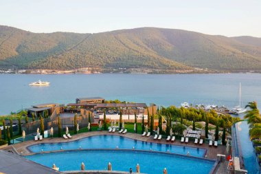 Bodrum, Türkiye - Ağustos 2020: Hotel Beach Lujo. Cennet 'te tatil. Güzel tropikal plaj afişi. Beyaz kum turizmi geniş panorama arka plan konsepti. İnanılmaz sahil manzaraları, yatlar.