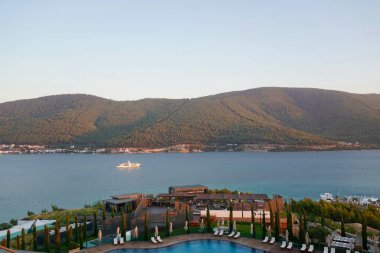 Bodrum, Türkiye - Ağustos 2020: Hotel Beach Lujo. Cennet 'te tatil. Güzel tropikal plaj afişi. Beyaz kum turizmi geniş panorama arka plan konsepti. İnanılmaz sahil manzaraları, yatlar.
