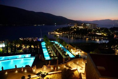 Geceleri cennet kumsalı, su üzerinde restoranda parlayan ışık, balayı için romantik bir yer, egzotik adada yaz akşamı.