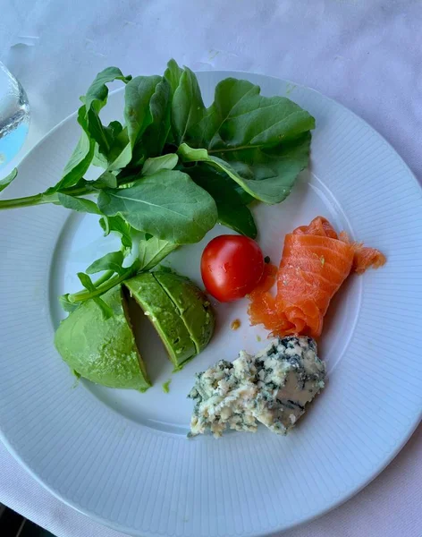 A white plate of healthy food on a table, Healthy food clean eating selection: Avocado Arugula Cherry Salmon Cheese, Vegan dinner eating — Stock Photo, Image