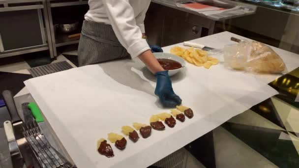 4K视频一个戴手套的男人做甜食：用热巧克力蘸几块芒果，放在桌上 — 图库视频影像