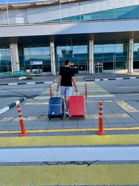 Μόσχα, Ρωσία - Αύγουστος, 2020: Αρσενικό μεταφέρει κόκκινες και μπλε αποσκευές στο δρόμο πριν από το ταξίδι — Φωτογραφία Αρχείου