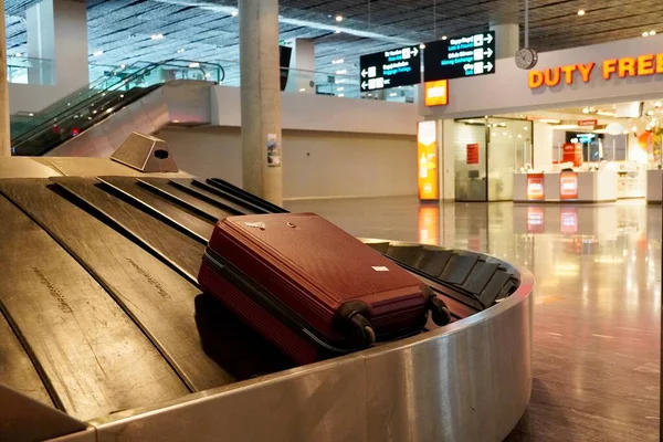 Csomagkihordó terület üres csomagtartóval a repülőtéren. Bőrönd a poggyászszállító övön a repülőtér poggyászfelvételi területén. — Stock Fotó