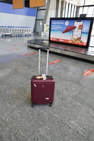 Бодрум, Турция - август 2020 года: Красный чемодан возле линии выдачи багажа в аэропорту, потерянный багаж. Чемодан в зале вылета аэропорта, концепция отдыха, чемоданы путешественников в ожидании терминала аэропорта — стоковое фото
