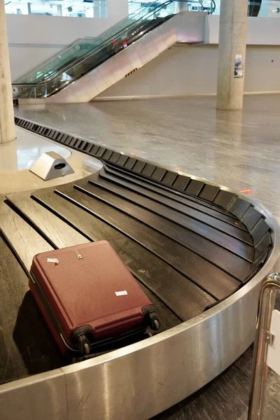 Csomagkihordó terület üres csomagtartóval a repülőtéren. Bőrönd a poggyászszállító övön a repülőtér poggyászfelvételi területén. — Stock Fotó