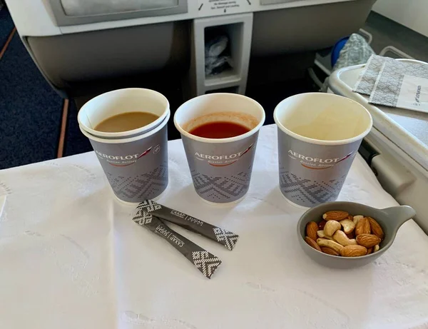 Москва, Россия - август 2020: Томатный сок и капучино с орехами на борту самолета Аэрофлота бизнес-класса — стоковое фото