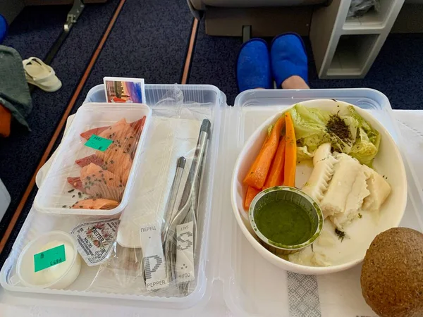 Москва, Россия - август 2020 г.: Человек, сидящий в кресле самолета. Обед для пассажиров авиакомпании на подносе. Ужин, напитки на борту. — стоковое фото