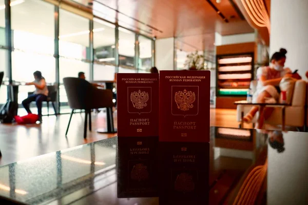 Útlevelek a világutazásra. Útiterv. Két piros útlevél az asztalon készen áll a bejelentkezésre a repülőtér társalgójában. Két orosz útlevél a reptéri társalgó hátterében — Stock Fotó