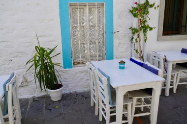 Otantik Bodrum Caddeleri Deniz kenarında. Mavi pencere, beyaz masalar geleneksel Türk Bodrum kafesi. Güzel Ege Denizi 'nin yakınındaki samimi açık kafe..