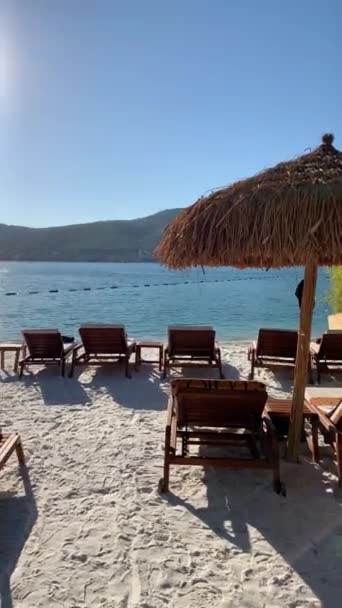 4K Smaragdlagune mit Blick auf die immergrünen Hügel mit schneeweißen Öko-Yachten, Liegestühlen und Bambusschirmen am weißen Strand des Lujo Luxury Hotel in der Türkei — Stockvideo