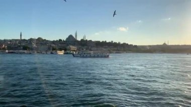 4K Tur gemisi İstanbul 'un günbatımındaki çarpıcı panoramik manzarasına bakan İstanbul Boğazı' nın zümrüt lagünü boyunca ilerliyor.