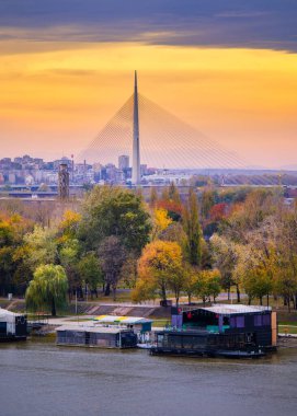 Belgrad / Sırbistan - 16 Kasım 2019: Sırbistan 'ın başkenti Belgrad' daki Sava nehrinin üzerinde renkli bir günbatımı ve arkada Ada köprüsü