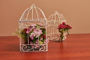 Çiçek buketi, kuş kafesi çiçek aranjmanı ve yanan mumla klasik düğün süsleri.