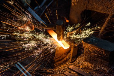 Demirci elle örsün üzerindeki erimiş metali havai fişeklerle dövüyor.