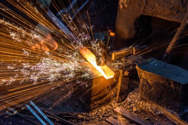 Demirci elle örsün üzerindeki erimiş metali havai fişeklerle dövüyor.