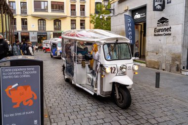 6 Aralık 2022 tarihinde İspanya 'nın Madrid kentindeki bir kaldırım taşı caddesindeki elektrikli tuk-tuk-tuk, turist turizminin popüler formu.