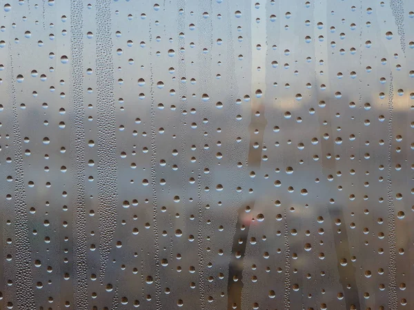 Misted window water drops on the background of the city.