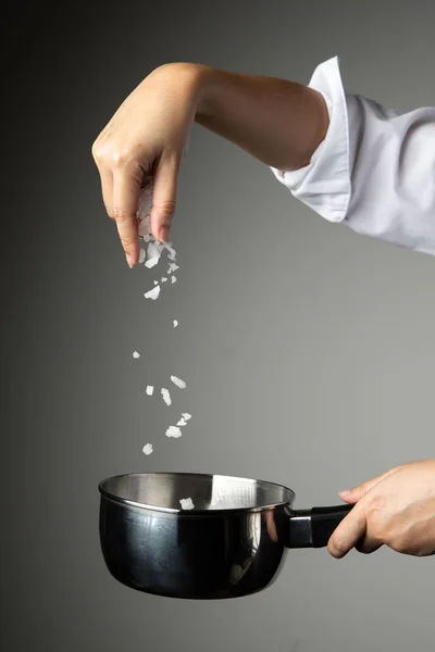 灰色の背景に調味料調理シェフ女性振りかける塩料理 — ストック写真