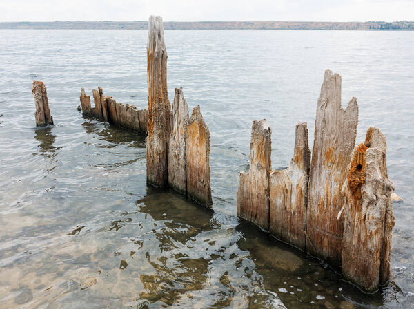 Salty estuary Kuyalnik, dead lake near Odessa, Ukraine. Wooden sticks reflected in blue water at sunny weather. 