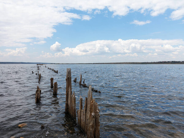 Salty estuary Kuyalnik, dead lake near Odessa, Ukraine. Wooden sticks reflected in blue water at sunny weather. 