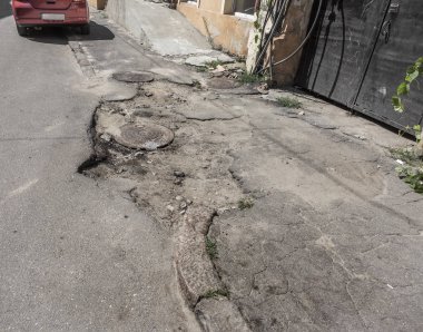 Kötü asfalt yol, çukurların ve lekeleri ile kırık asfalt zarar görmüş. Büyük delikli çok kötü asfalt yol yol çukuru kanalizasyon ambarda. Çok sayıda tehlikeli hataları