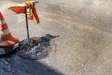 Su temini, kanalizasyon kaza. Su çeşme altından yol kanalizasyon dökülen. Atılım kanalizasyon sistemine. Kanalizasyon kapağı yolu üzerindeki su akar
