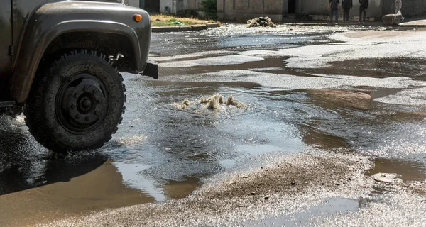 Water flows out of drainage hatch. Drainage fountain of sewage. Accident in sewage system. Dirty sewer water flows fountain on road. Drainage system for wastewater discharge does not work