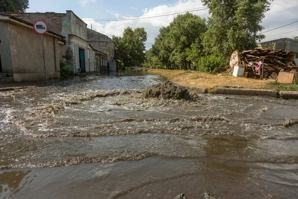 Water flows out of drainage hatch. Drainage fountain of sewage. Accident in sewage system. Dirty sewer water flows fountain on road. Drainage system for wastewater discharge does not work