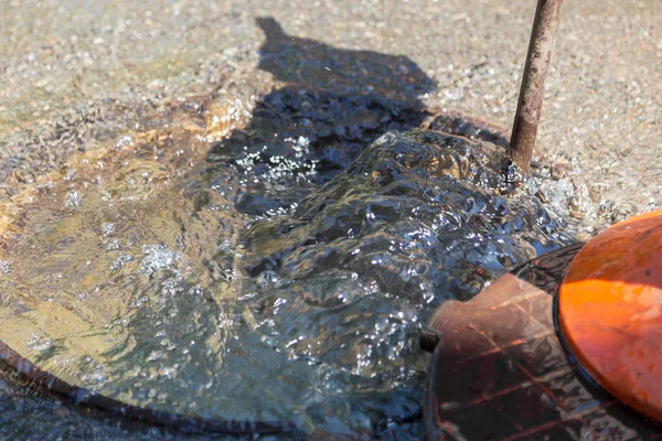 Accident of water supply, sewage. Water fountain pours out from under the road sewer. Breakthrough sewerage system. Water flows on the road from the sewer hatch