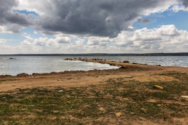 Keçi sürüsü sıcaktan göl kıyısı şiş kaydedilir. Çiftlik hayvanları, keçi göle yağmur önce yanmış kıyısında. Nehir kıyısında keçi sürüsü kümesine