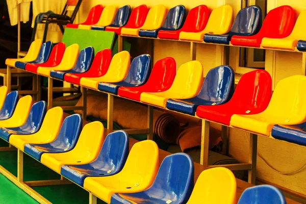 スタジアムのスタンドの多色空のプラスチックの椅子 スタンドの観客の多くの空席 ジムでサッカーファンのための空のプラスチックの椅子 スタジアムのファンのために明るくカラフルな席 — ストック写真