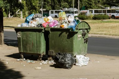 Çöp konteyneri, çöp ile kalabalık. Yolda terkedilmiş katı ev çöp. Çevre kirliliği. Ekolojik sorun. Terk edilmiş çöp yolda. Büyük bir şehirde atık yönetimi sorunu