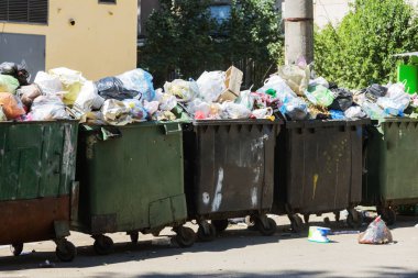 Çöp konteyneri, çöp ile kalabalık. Yolda terkedilmiş katı ev çöp. Çevre kirliliği. Ekolojik sorun. Terk edilmiş çöp yolda. Büyük bir şehirde atık yönetimi sorunu