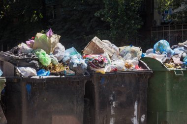 Çöp konteyneri, çöp ile kalabalık. Yolda terkedilmiş katı ev çöp. Çevre kirliliği. Ekolojik sorun. Terk edilmiş çöp yolda. Büyük bir şehirde atık yönetimi sorunu